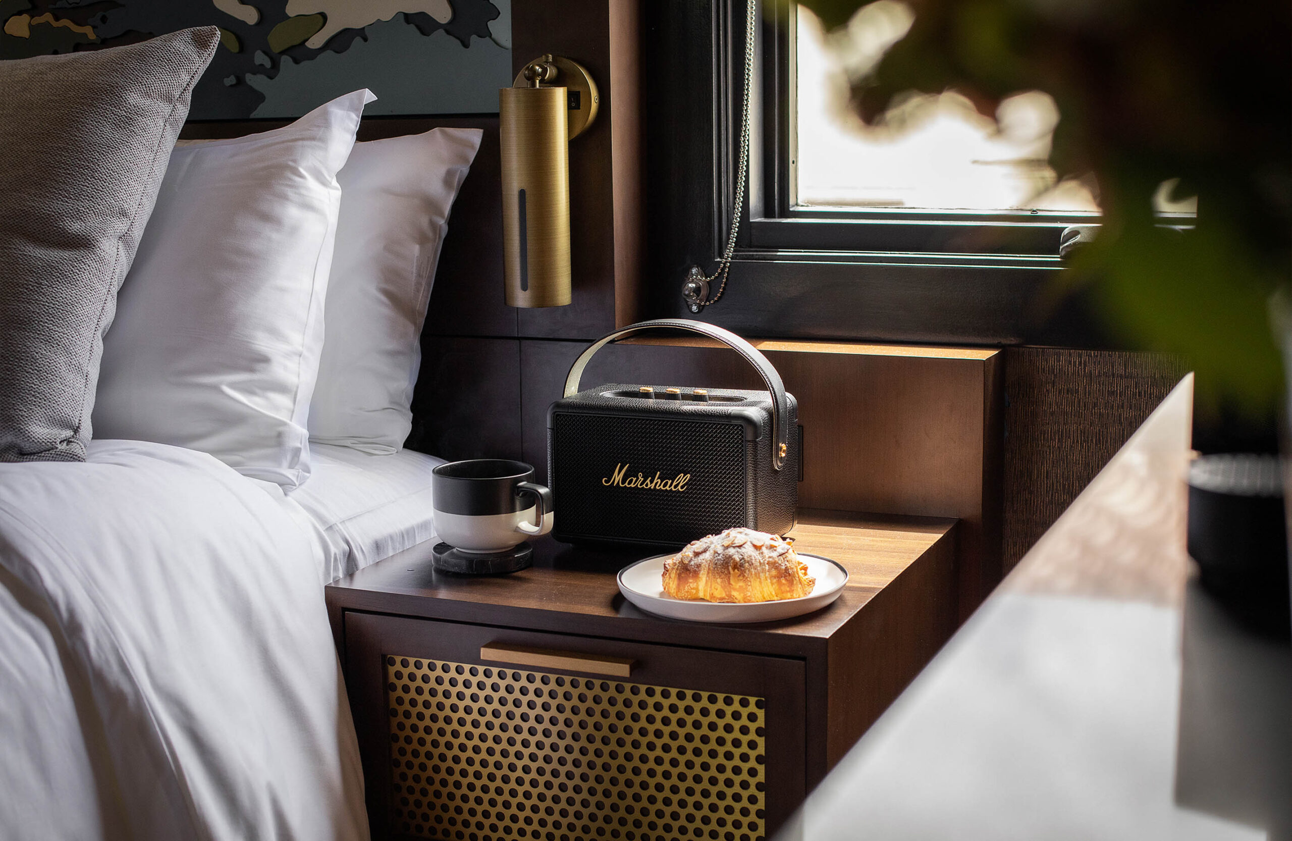 Bedside table with coffee, pastry and speaker in The Irving Gill Penthouse at Orli La Jolla boutique hotel
