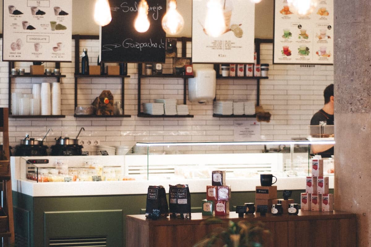 Modern café interior with espresso counter, menu boards, hanging lights, and packaged coffee products on display