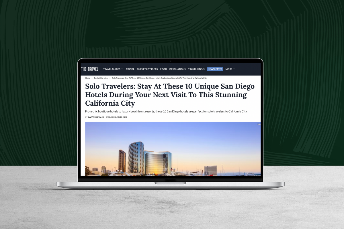 Laptop displaying an online travel article about unique San Diego hotels, set against a dark green textured background