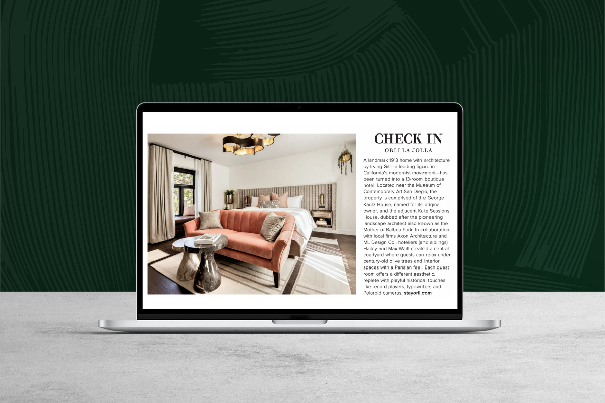 Laptop displaying a digital magazine feature showcasing a stylish hotel living space against a dark green textured background