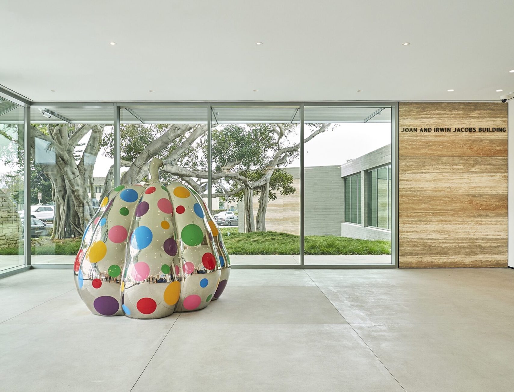 Modern interior space featuring a colorful polka-dot art sculpture with floor-to-ceiling windows overlooking greenery