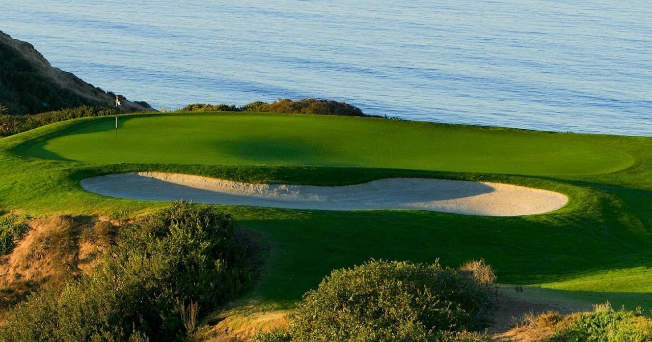 Oceanfront golf green with sand bunker overlooking the Pacific, featuring manicured fairways and coastal scenery at a luxury seaside golf course.