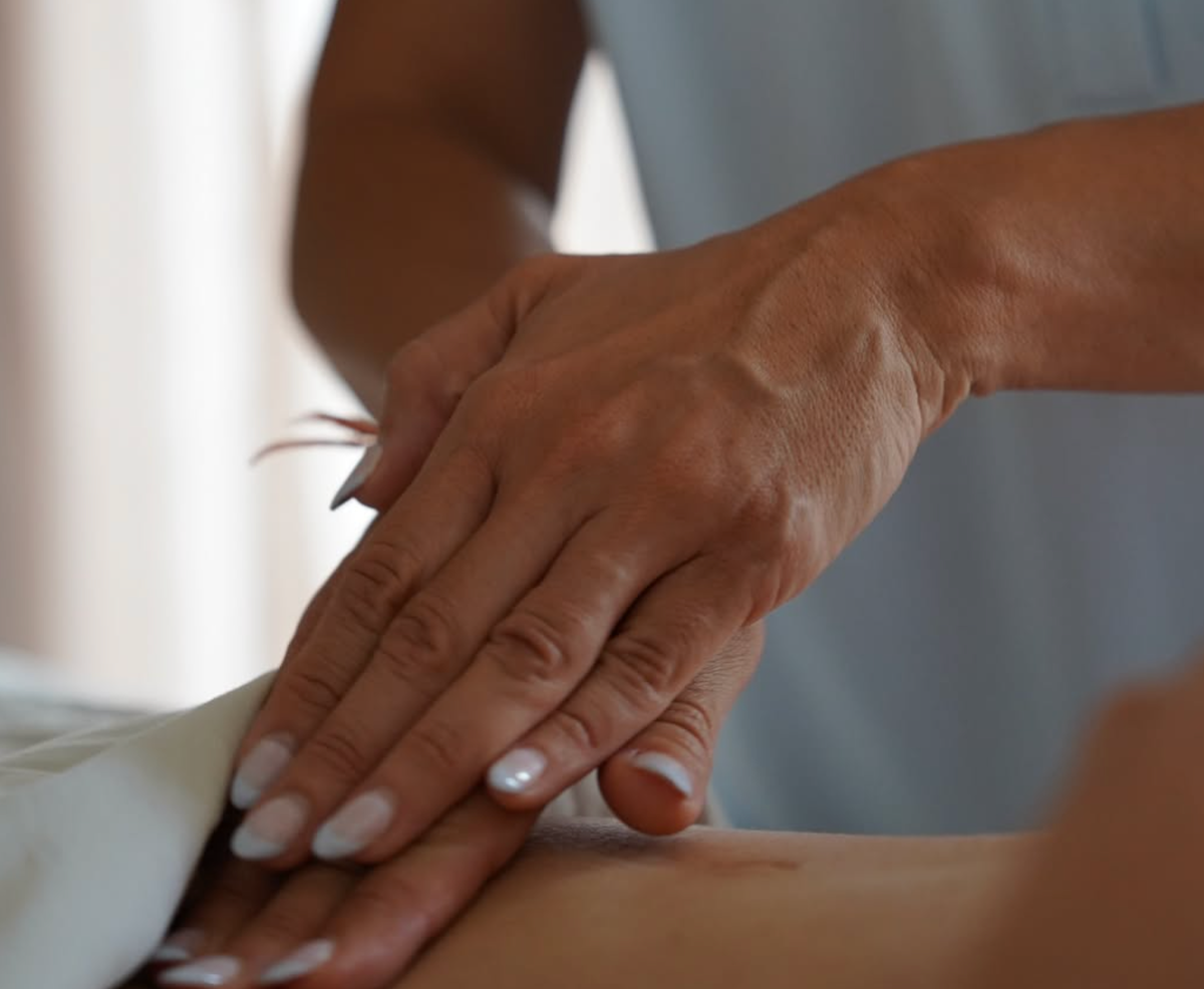 Close-up of hands giving a massage on a person’s back, suggesting a spa or wellness treatment.