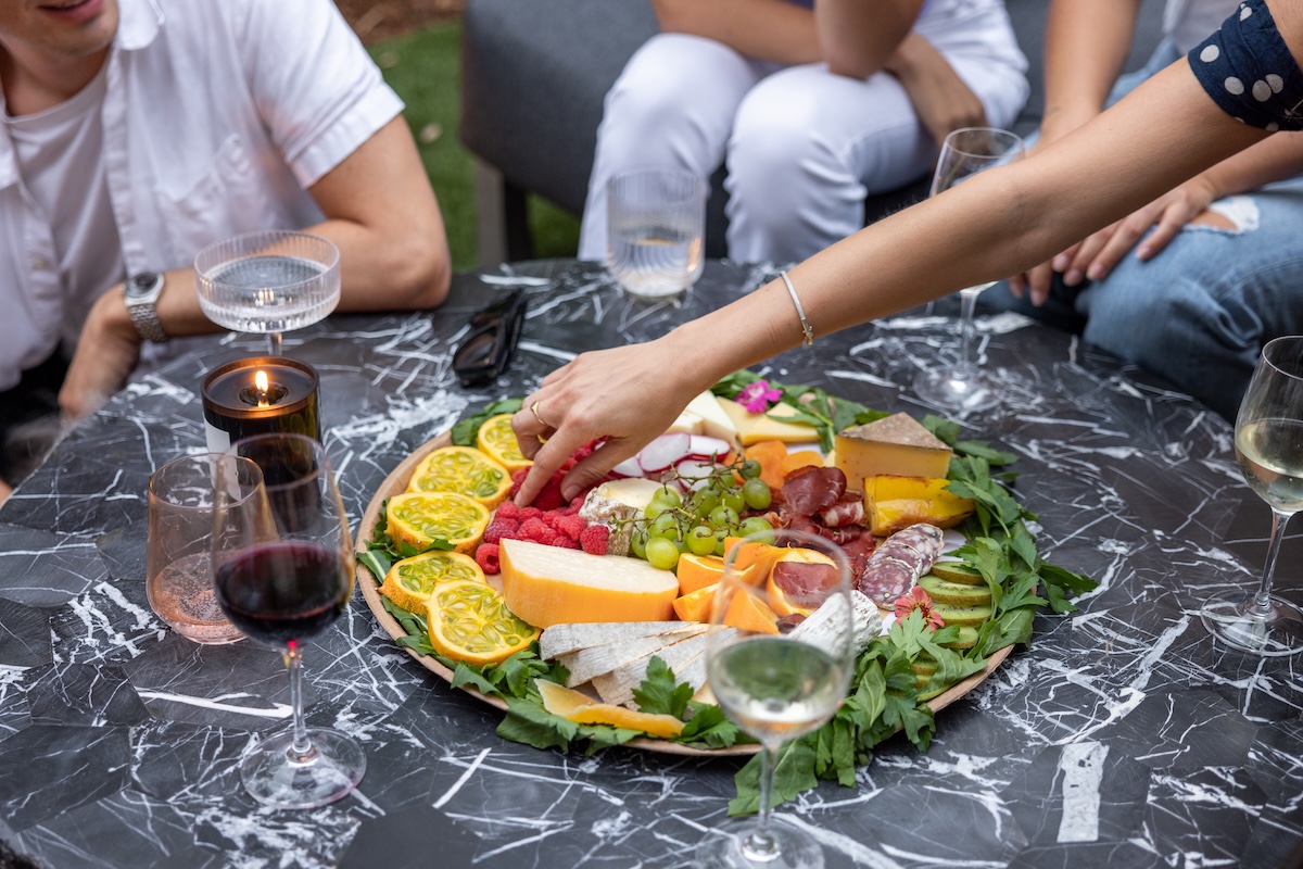 Orli Exterior 18 Guests enjoying wine and a colorful charcuterie board at an outdoor gathering.